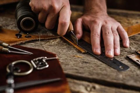 Close up of a shoemaker or artisan worker hands. Leather craft tools on old wood Stock Photos