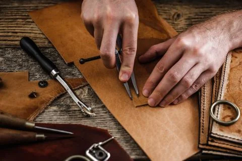 Close up of a shoemaker or artisan worker hands. Leather craft tools on old wood Foto stock