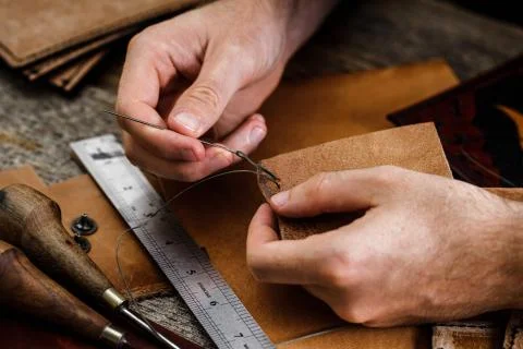 Close up of a shoemaker or artisan worker hands. Leather craft tools on old wood Stock Photos