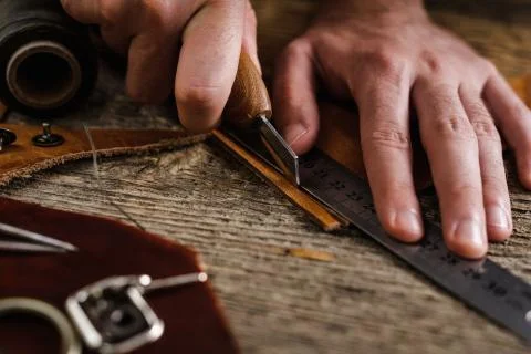 Close up of a shoemaker or artisan worker hands. Leather craft tools on old wood Stock Photos