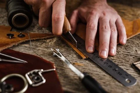 Close up of a shoemaker or artisan worker hands. Leather craft tools on old wood Stock Photos
