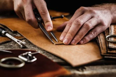 Close up of a shoemaker or artisan worker hands. Leather craft tools on old wood Stock Photos