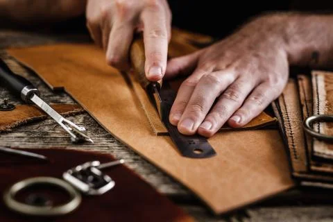 Close up of a shoemaker or artisan worker hands. Leather craft tools on old wood Stock Photos