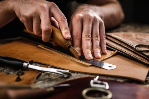 Close up of a shoemaker or artisan worker hands. Leather craft tools on old wood Foto stock