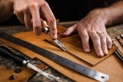 Close up of a shoemaker or artisan worker hands. Leather craft tools on old wood Stock Photos