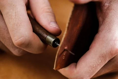 Close up of a shoemaker or artisan worker hands. Leather craft tools on old wood Stock Photos