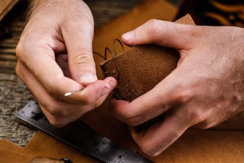 Close up of a shoemaker or artisan worker hands. Leather craft tools on old wood Stock Photos