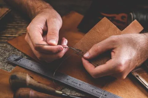 Close up of a shoemaker or artisan worker hands. Leather craft tools on old wood Stock Photos