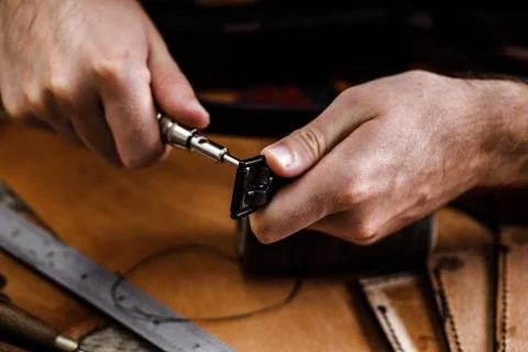 Close up of a shoemaker or artisan worker hands. Leather craft tools on old wood Stock Photos