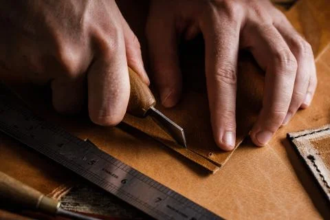 Close up of a shoemaker or artisan worker hands. Leather craft tools on old wood Stock Photos