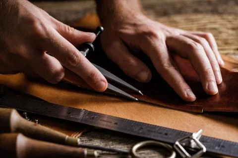 Close up of a shoemaker or artisan worker hands. Leather craft tools on old w Foto stock