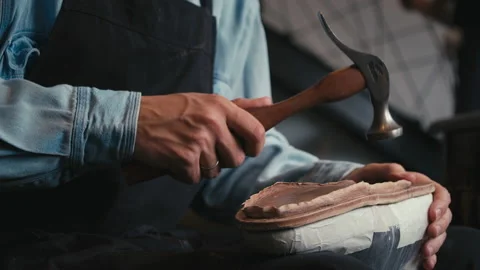 Close up shoemaker taps sole shoes with hammer. Workshop for production shoes Stock Footage 138262033
