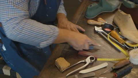 Close up shoemaker's hands sharpening a knife on table in Shoe workshop Video stock 137578873