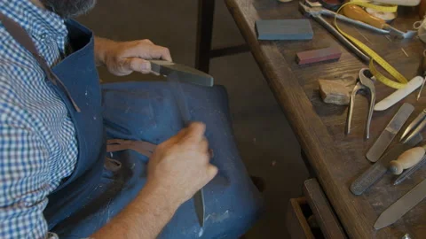 Close up shoemaker's hands sharpening tool in Shoe workshop. Shoemaker sews Stock Footage 137579113