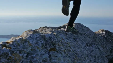 Close-up on the shoes and legs of a man running on a mountain crest Stock Footage