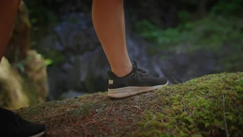 Close up of shoes walking to cliff edge, waterfall in background 库存影片 220301706