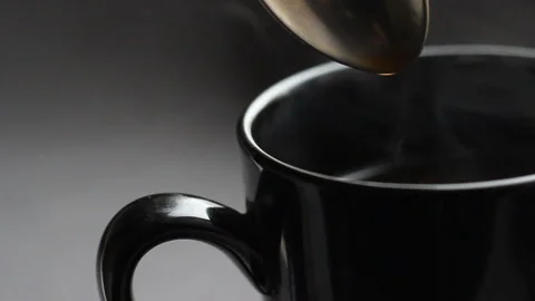 Close up shoot with black cup of coffee. Stir the cappuccino with a spoon Stock Footage 86011045