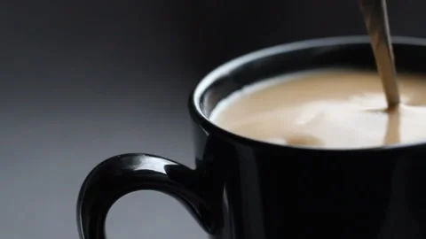 Close up shoot with black cup of coffee. Stir the cappuccino with a spoon Stock Footage 86011051