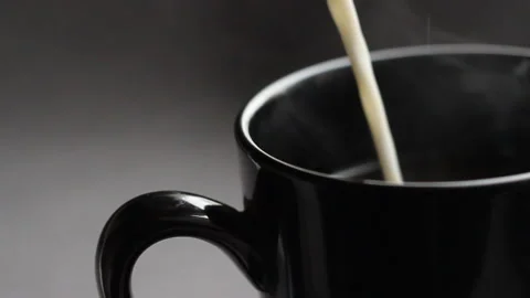 Close up shoot with black cup of coffee. Slow motion effect with pour in milk Stock Footage 86011110