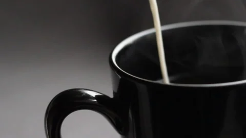Close up shoot with black cup of coffee. Slow motion effect with pour in milk Stock Footage 86011136