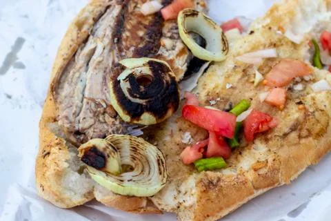 Close-up shoot of fish and bread food with tomato, onion, pepper on the stree Stock Photos
