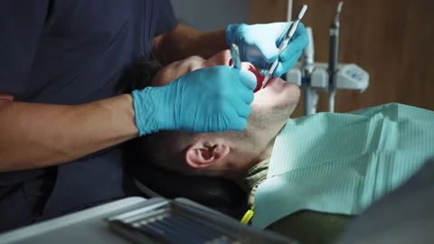 Close-up shooting of man in dental bib lying on chair during dental check-up Stock Footage 246746904