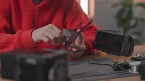 Close-up shooting of young man sitting at desk, holding all elements of drone in Stock Footage 194401869