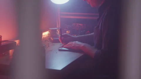 Close up of Shop Worker Unscrewing Back on Computer in Lamp Light Through Window Video stock 208785104
