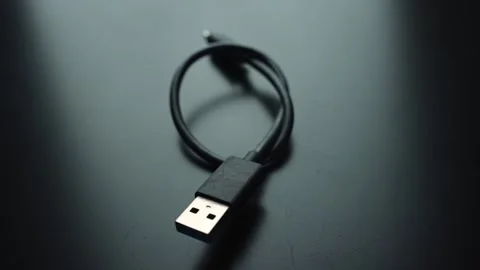 Close-up of a short USB charging cable with USB-A plug on a dark desk, shallow Vídeos de archivo 329470421