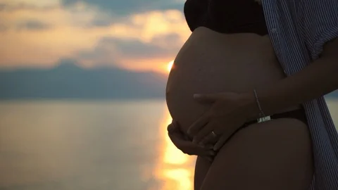 Close-up shot of amazing tiny pregnant belly on the background of pink and 스톡 동영상 114771698