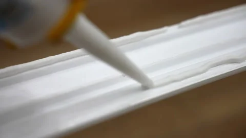 Close up shot of applying white glue on plastic surface of decorative baseboard Stock-Footage 208420457