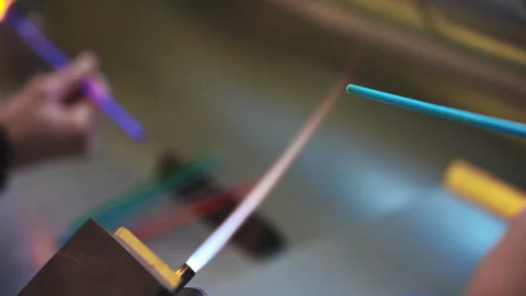 Close up shot of an artisan handling a glowing crystal glass stick over a Vidéo 339377680