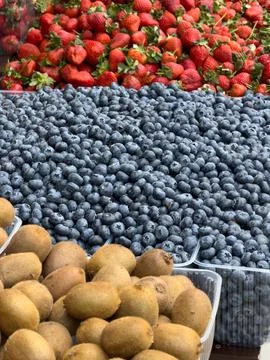 Close-up shot of assorted fresh berries and kiwis at farmers market stall Stock Photos