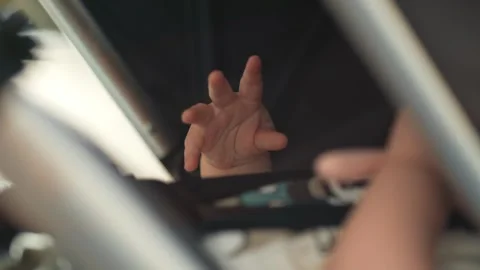 A close-up shot of a baby’s tiny hands resting peacefully in a stroller. The rel Video stock 284887345