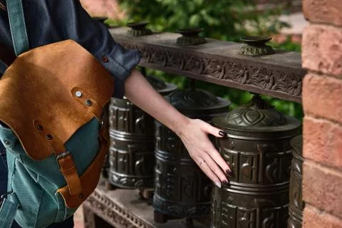 Close shot from the back of a backpack and female hand on a Mani prayer wheel Stock Photos
