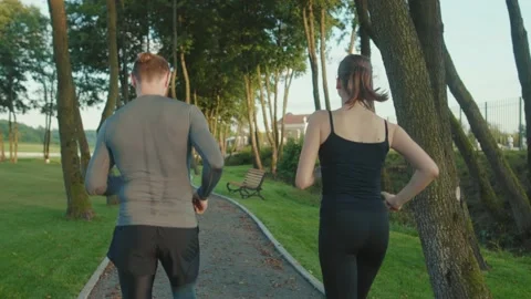 Close up shot back man and woman running in park together jogging at outdoor Stock Footage 138644589