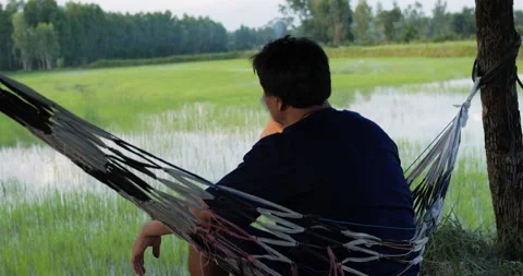 Close up shot, Back of Young farmer man sitting on the hammock and look out 库存影片 202119774