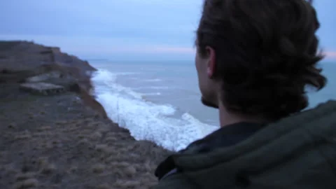 Close shot from a backside of troubled young guy hiking on a coastline alone Stock Footage 151607029