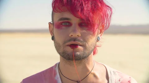 Close-up shot of a badly wounded young man with red dyed hair, punk hairstyle Stock Footage 293114930