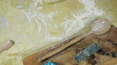 Close-up shot of a baker rolls out the dough with a rolling pin on the table. Video stock 169358326