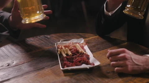 A close-up shot of a bar table with a plate of charcuterie snacks and a two Video stock 284089129