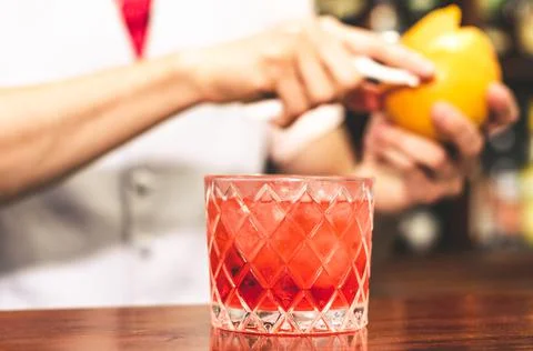 Close up shot of bartender hands preparing negroni cocktail with grapefruit. He Stock Photos