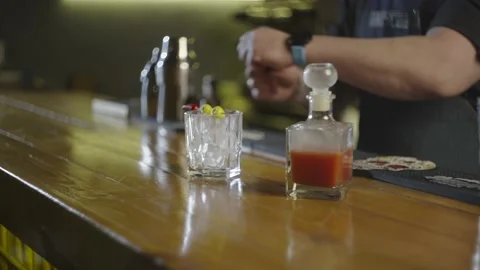 A close-up shot of a bartender setting a glass with ice and a skewer with pepper Stock Footage 236538193