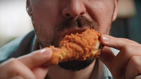 Close up shot of bearded man face man holding and biting chewing fried chicken Stock Footage 305494918