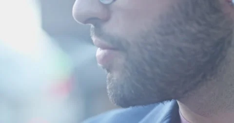 A close-up shot of a bearded man's face while smoking a cigarette, highlighting Vidéo 276856979