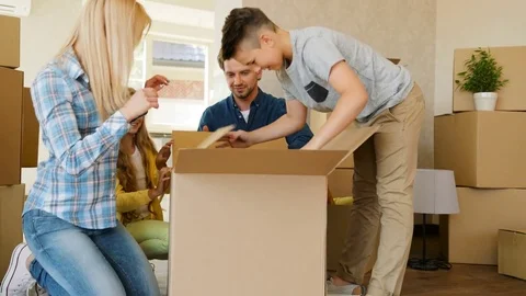 Close up shot of beatiful happy family opening big cardboard box while they Stock Footage