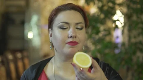 Close up shot beautiful middle aged brunet woman eating biting lemon cringing sm Stock Footage 137537377