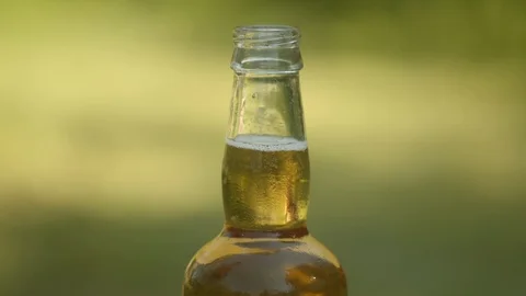 Close up shot of beer bottle with female hand removing to take a drink, 4k Stock Footage 112763531