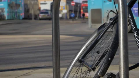Close Up Shot of Bicycle Locked to Rack as Bus Drives Past In Background. High Stock Footage 167554993