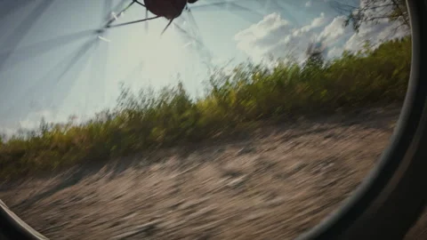 A close-up shot of a bicycle wheel as it spins along a dusty trail. A travel Stock Footage 323723187